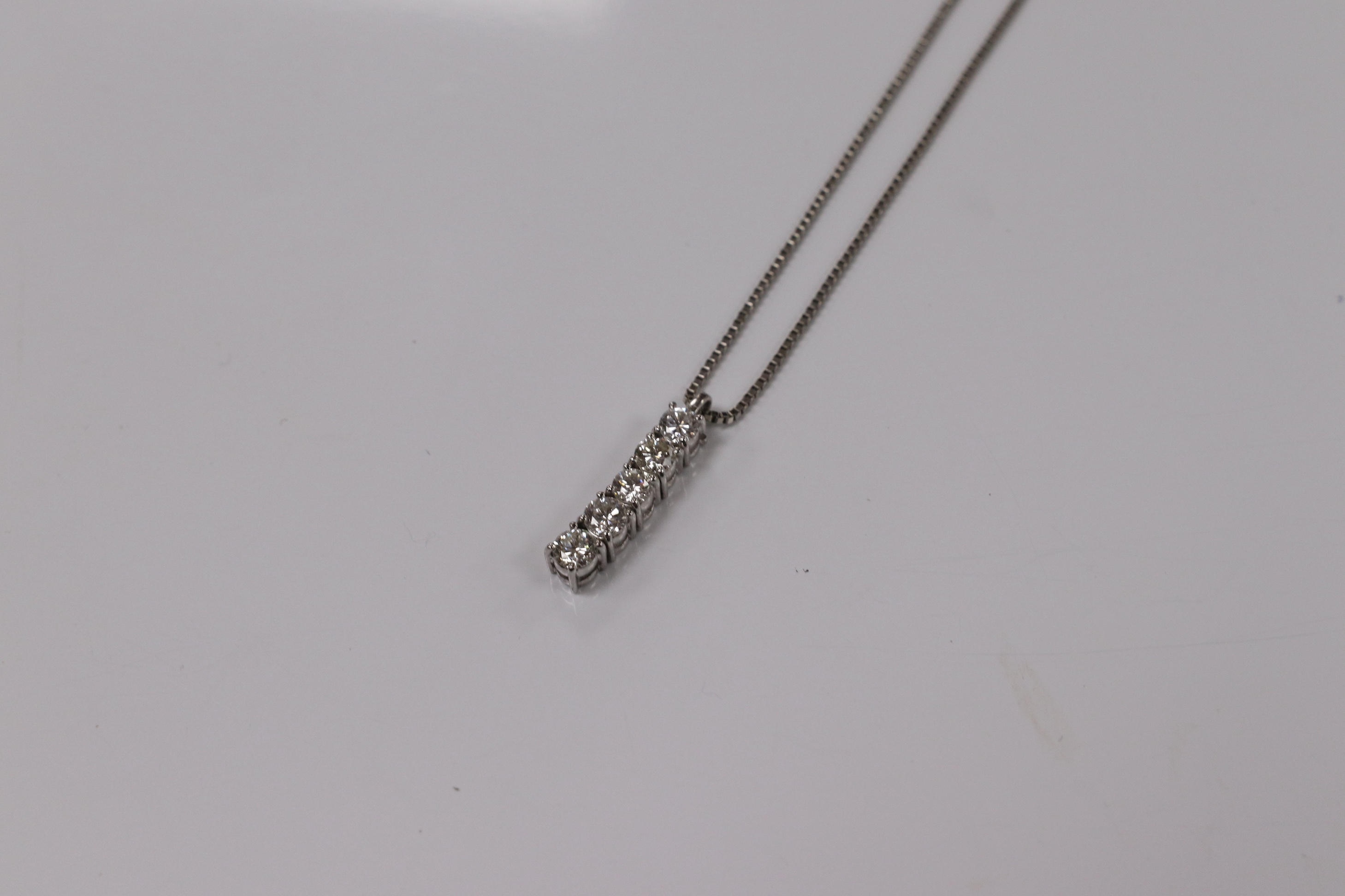 A modern white metal (stamped PT900) and five stone diamond set line pendant, on white metal (stamped pt850), overall 49cm, gross weight 4.9 grams. Condition - fair to good